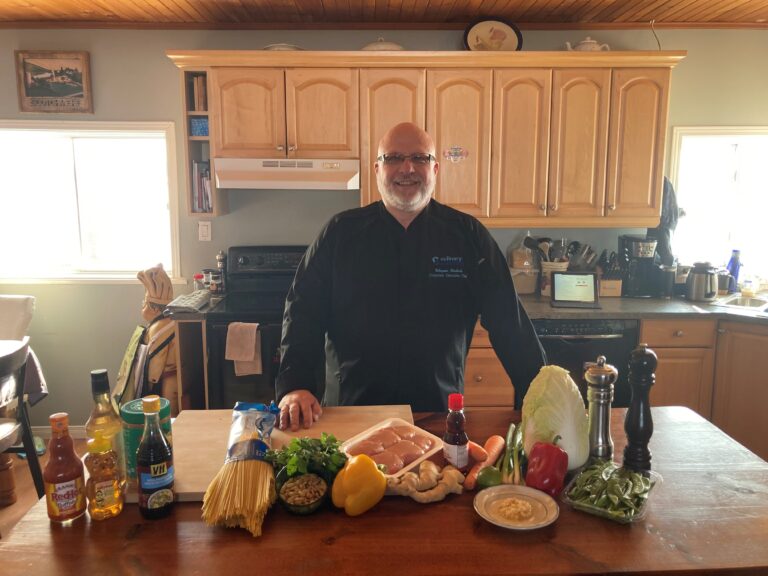 Une photo du chef Wayne debout dans une cuisine avec quelques ingrédients devant lui